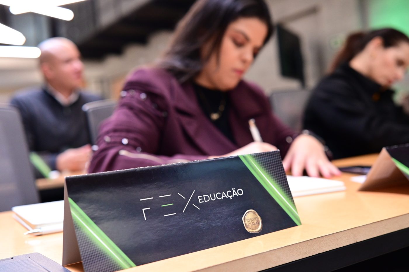 Executiva anotando durante o CAFEX ao lado do material da Faculdade FEX Educação